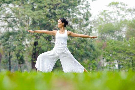 Beautiful woman practicing yoga in the park. Warrior Two/ Virabhadrasana II.の写真素材