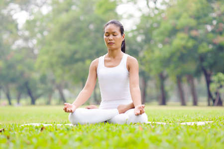 Beautiful woman practicing yoga in the parkの写真素材