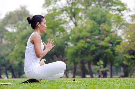 Beautiful woman practicing yoga in the park.Half Lotus Toe Balance / Pandangustha Padma Utkatasana.の写真素材
