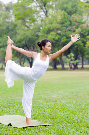 Beautiful woman practicing yoga in the park.Natarajasana / Lord Shiva Dancing Pose.の写真素材