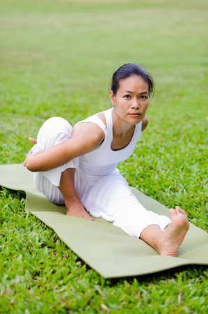 Beautiful woman practicing yoga in the park.Pose Dedicated to the Sage Marichi I /
Marichyasana I.の写真素材