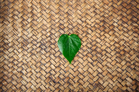 Fresh heart shape leaf on bamboo mat backgroundの写真素材