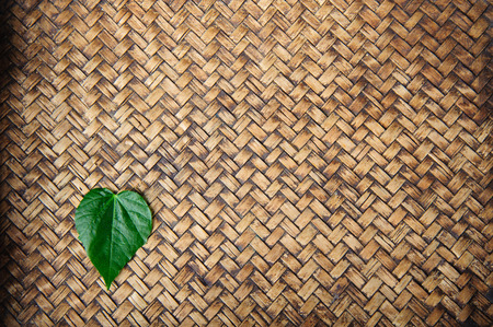 Fresh heart shape leaf on bamboo mat backgroundの写真素材