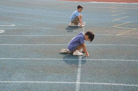 Two boys run competition on the green trackの写真素材