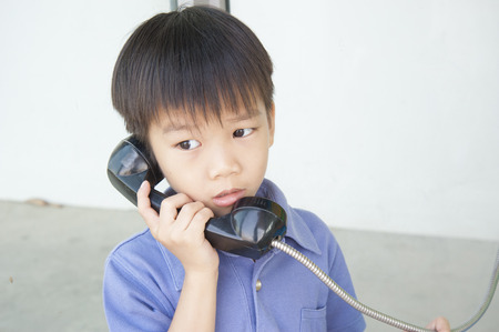Boy using the old public phone boothの写真素材