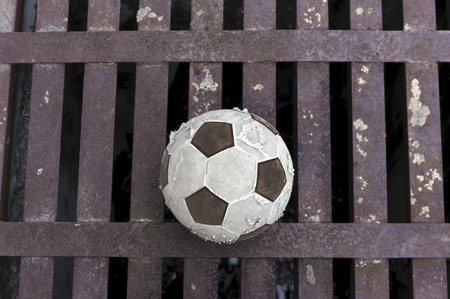 Old football ball on rust iron bar backgroundの写真素材