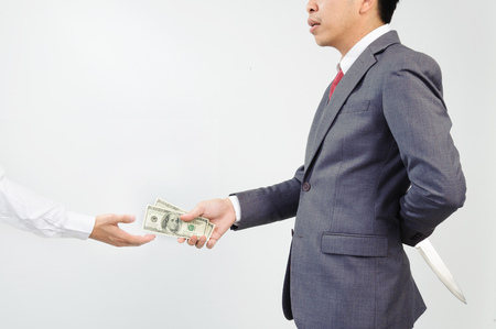 Man giving money to other but hide knife at his backの写真素材