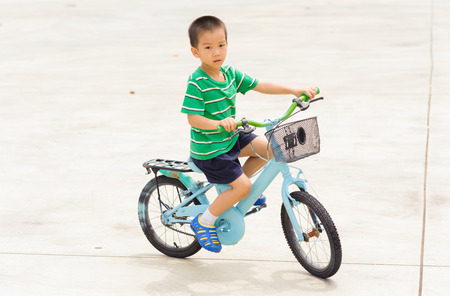 Boy rid bicycle on concrete floor on the dayの写真素材