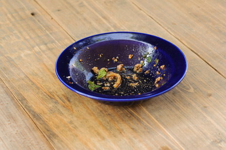 Waste of food in dirty blue bowl on wooden floorの写真素材