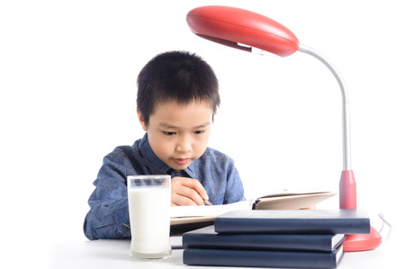 Young boy has a cup of milk reading book on white background