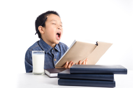 Young boy has a cup of milk reading book on become boring white background