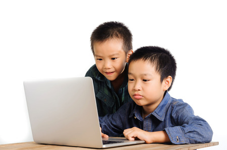 Two boys using and sharing notebook on wood deskの写真素材