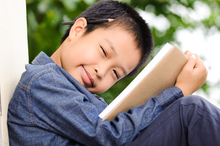 Young boy reading books in gardenの写真素材