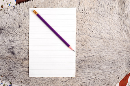 Pencil and  old page ripped off from the notebook on white fur cow skinの写真素材