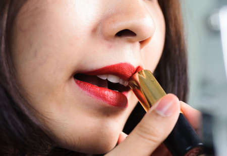 Thin focus at lip Beautiful young woman apply red lipstickの写真素材