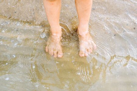 Boy feet on the sand beach and sea