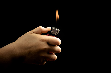 Dark tone effect Asian boy hand lighter on black backgroundの写真素材