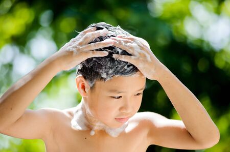 Asian young boy washing hair foam on green bokeh background