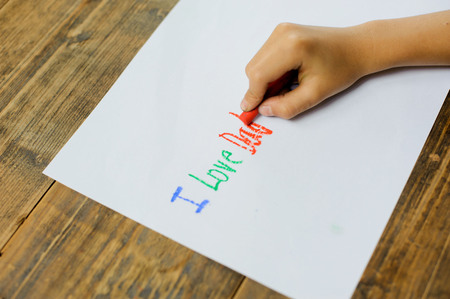 Focus on kid hand use crayon color write text on white paper. I love dad.の写真素材