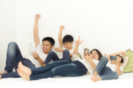 Out focus, Family in living room using smartphone and tablet device each one separately. Social network concept.の写真素材
