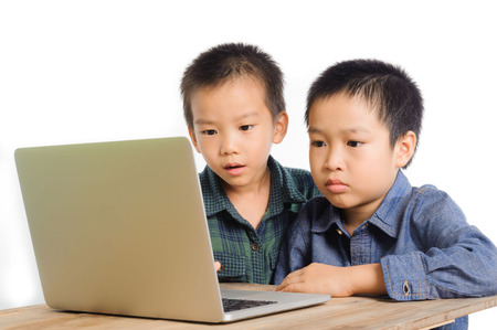 Two boys using and sharing notebook on wood desk