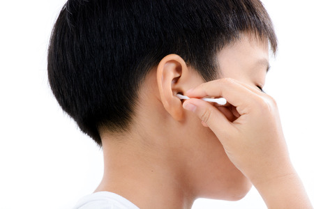 Young asian boy use white cotton bud to clean his ear by himselfの写真素材