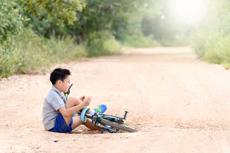 Young Asian boy got accident and fall from the bicycle and feel pain. Transportation and safety concept.の写真素材