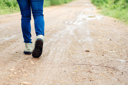 Woman traveller in boot walk on the wet dirty road in urban forest.の写真素材