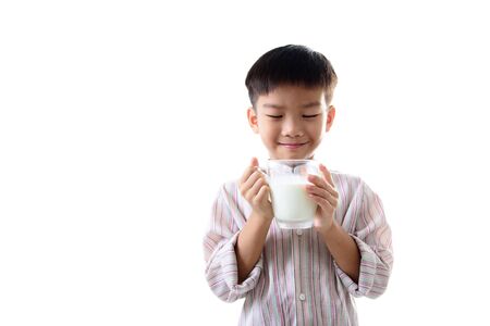 Young Asian boy carry a glass of milk looks happy. Health concept.の写真素材