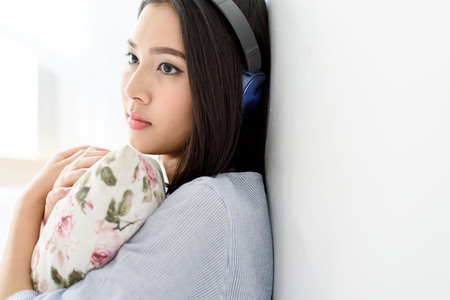 Selective focus on girl face that using blue headphone to listen music from mobile phone device....