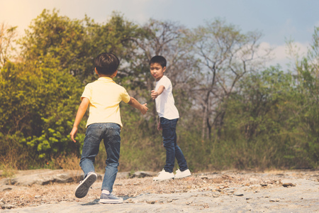 Vintage color, Two Boy walking through the rough rocky land in the day time with strong sunlight.の写真素材