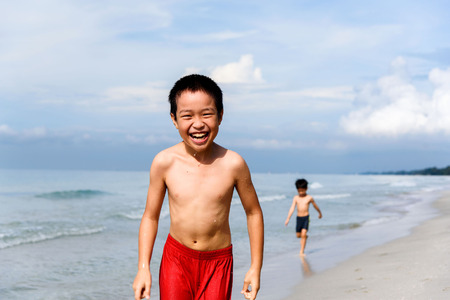 Boy in swim suit run in on the beach and sea at Thai island.の写真素材