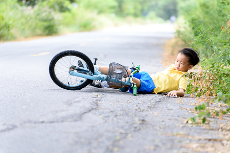 Young Asian boy got accident and fall from the bicycle and feel pain. Transportation and safety concept.の写真素材