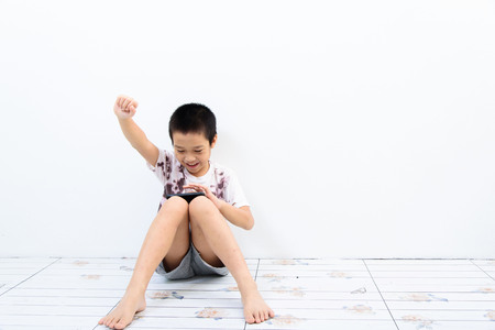 Younger Asian poor boy got a new smartphone and looks happy. Social network concept.の写真素材