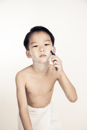 Dark tone effect, Young boy is shaving his face in the bathroom.の写真素材
