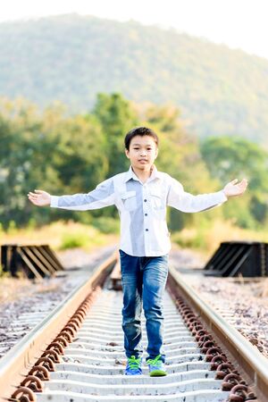 Young asian Thai boy walking on the railway at the country side of Thailand with forest backgroundの写真素材