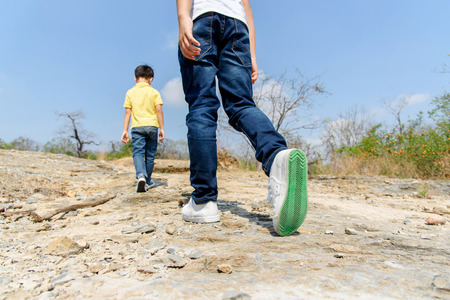 Two Boy walking through the rough rocky land in the day time with strong sunlight.の写真素材