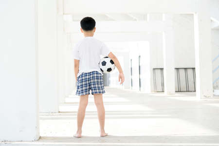 Young Asian boy carry football in the empty white building.の写真素材