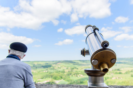 Selective focus at telescope beside the old man at the public tourist area and blue sky white cloud.