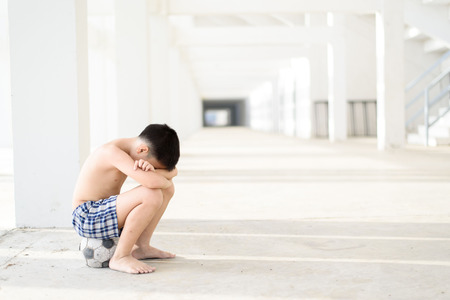 Young Asian boy sit on the old football alone in the white building.の写真素材