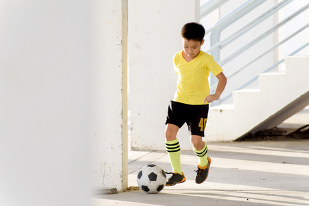 Young Asian boy play football in the empty white building.の写真素材