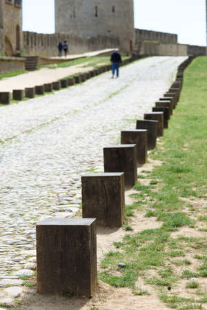 Selective focus at the first old wooden pole beside the stone road and grass.の写真素材