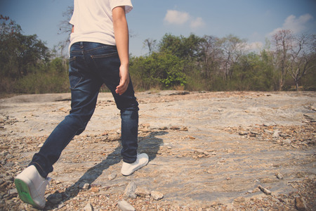 Vintage color, Kids in blue jean walking through the rough rocky land in the day time with strong sunlight.の写真素材