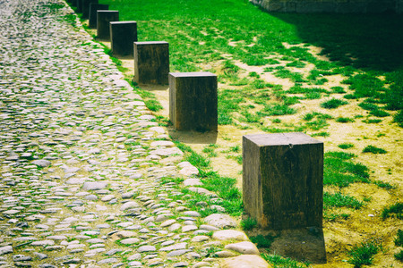 Vintage color tone and vignetted effect. Selective focus at the first old wooden pole beside the stone road and grass.の写真素材