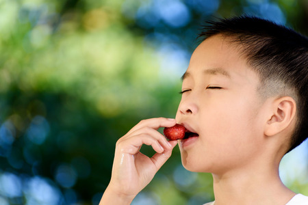 Young Thai boy eat strawberry with happy face.の写真素材