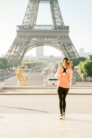 Warm tone of Selective focus at woman running infront of tour Eiffel in the morning. Eiffel tower is...