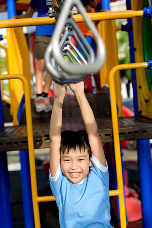 Young asian boy hang the bar by his hand to exercise at out door playground
