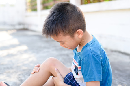 Young Asian Thai pain on his knee accident and cry on the concrete floor.の写真素材