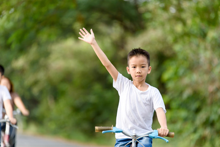 Young Asian Thai boy riding bicycle in the park and touch flower of grass with family.の写真素材