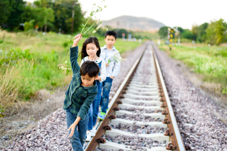 Young asian Thai boy and girl walking on the railway at the country side with forest backgroundの写真素材